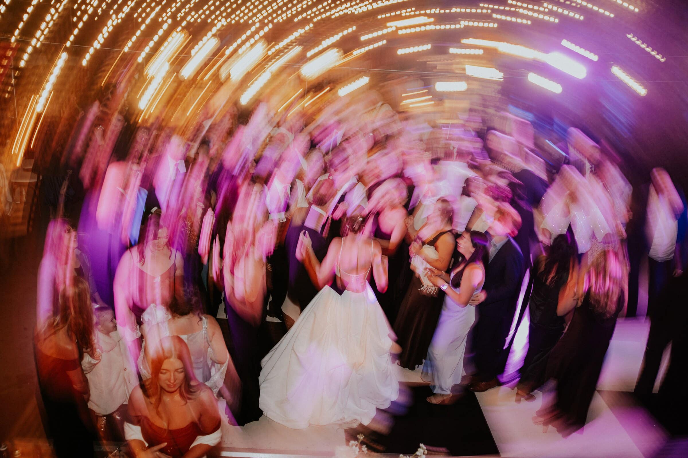 The crowded dance floor in a swirl of pink and gold light
